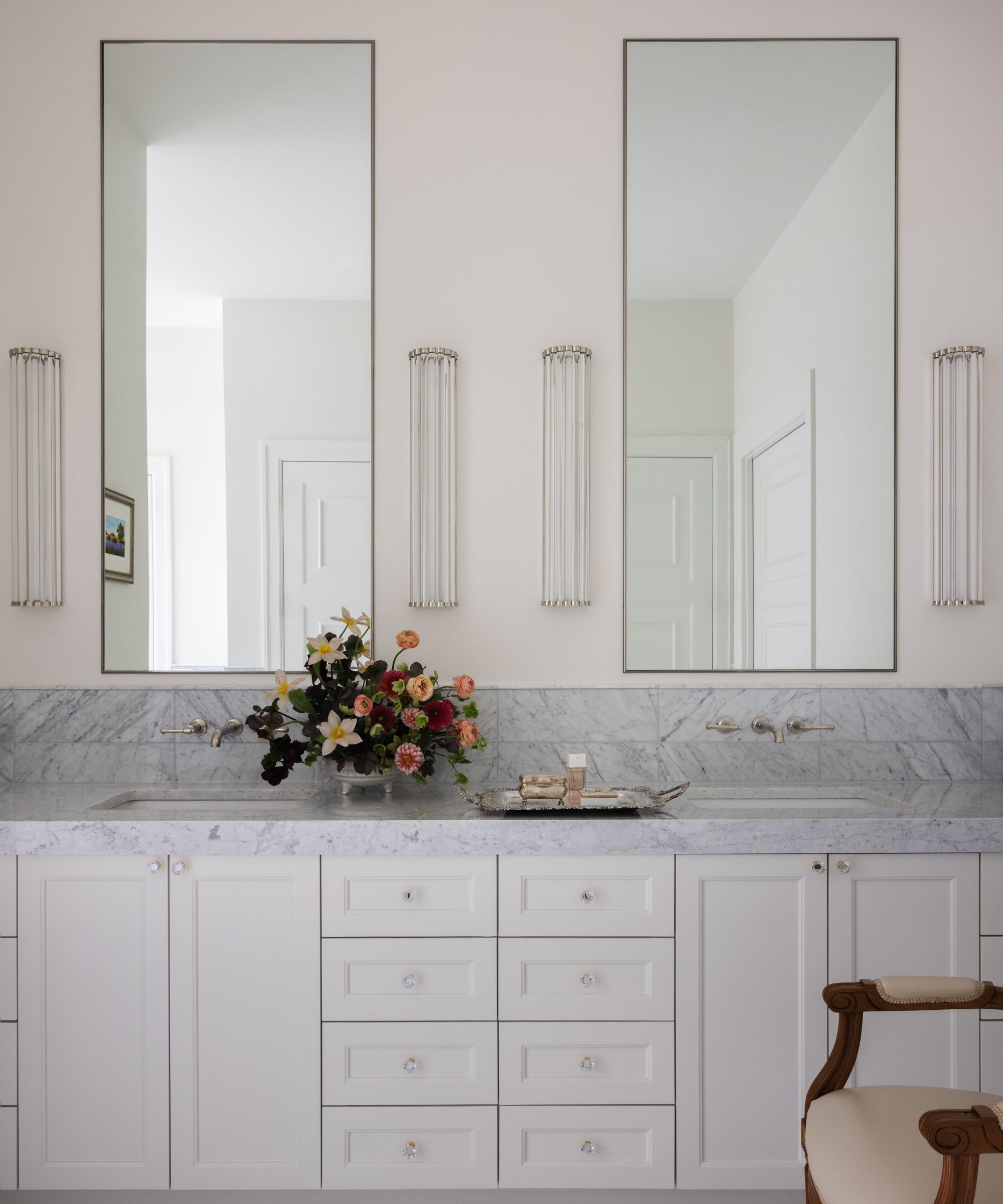 A white bathroom with a white vanity and marble countertops