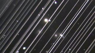 The image shows diagonal lines caused by the light reflected by a group of 25 Starlink satellites passing through the field of view of a telescope at Lowell Observatory in Arizona during observations of the NGC 5353/4 galaxy group on May 25, 2019.