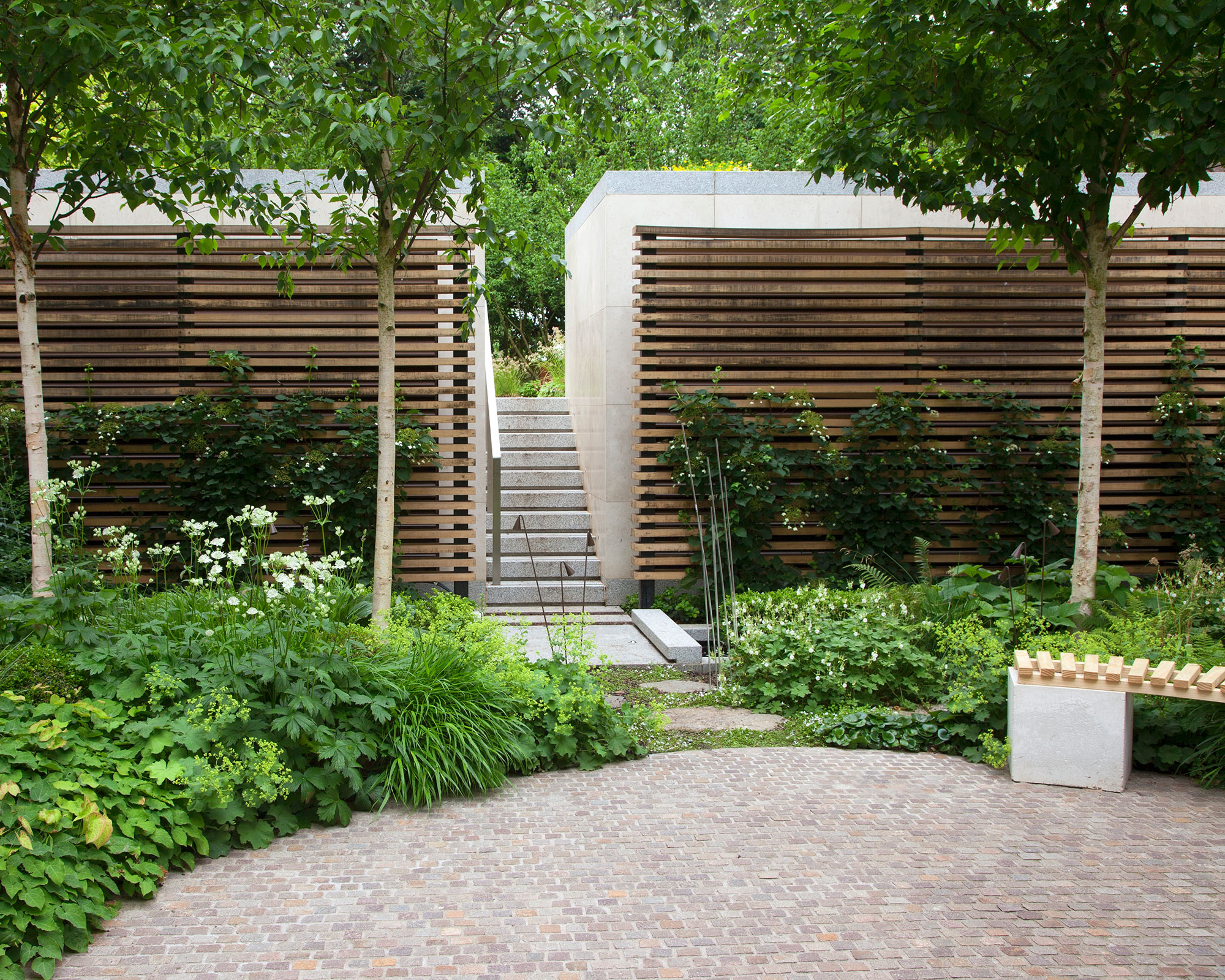 brick paved patio surrounded by lush green planting