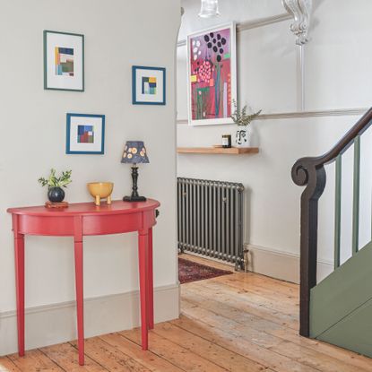 Large hallway with wooden flooring and colourful furniture, with a black radiator in the background