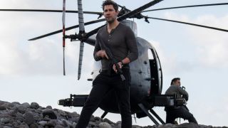 John Krasinski stands armed in front of a helicopter in Tom Clancy's Jack Ryan.