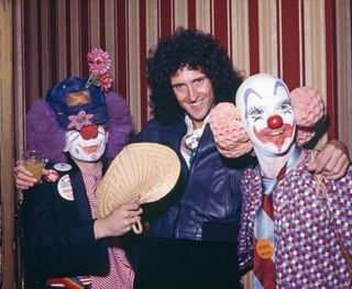 Brian May with a pair of party guests dressed as clowns