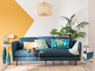 Color blocking trend in a living room with a yellow wall and blue sofa