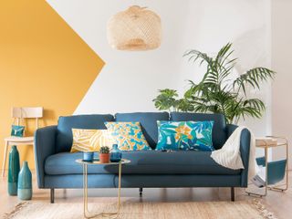 Colour blocking trend in a living room with a yellow wall and blue sofa