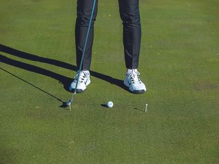 Gary Munro demonstrating a putting technique drill using two tees and a golf ball