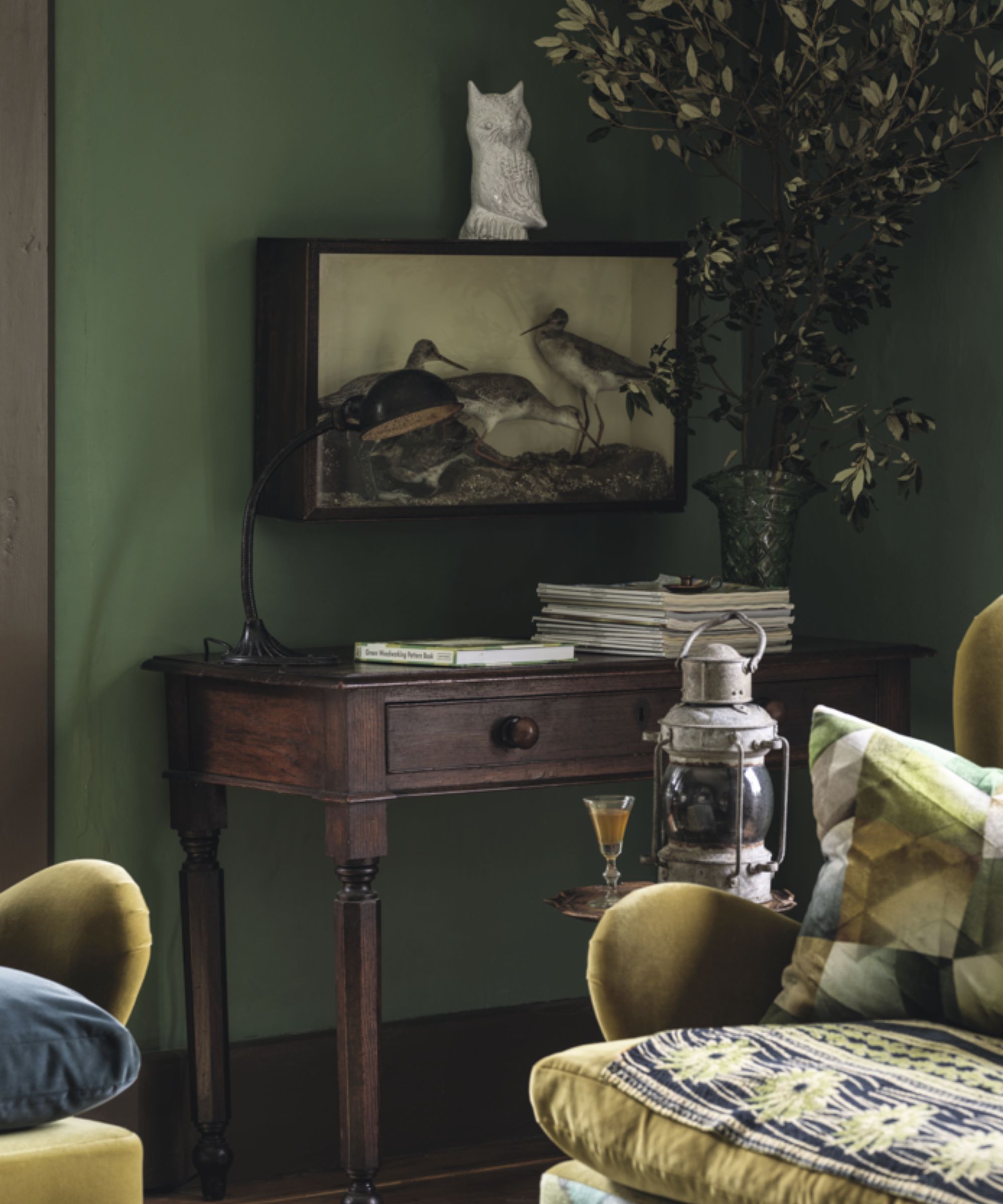 Olive green living room with yellow velvet sofas and a wood desk