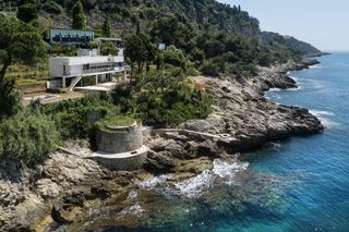 A villa on a cliff side with a view of the shore line and ocean.