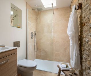 shower room with exposed stone wall and large format stone wall tiles and Farrow & Ball paint