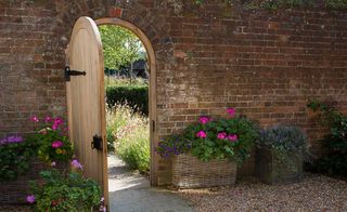 arched doorway in old brick wall with view into garden beyond