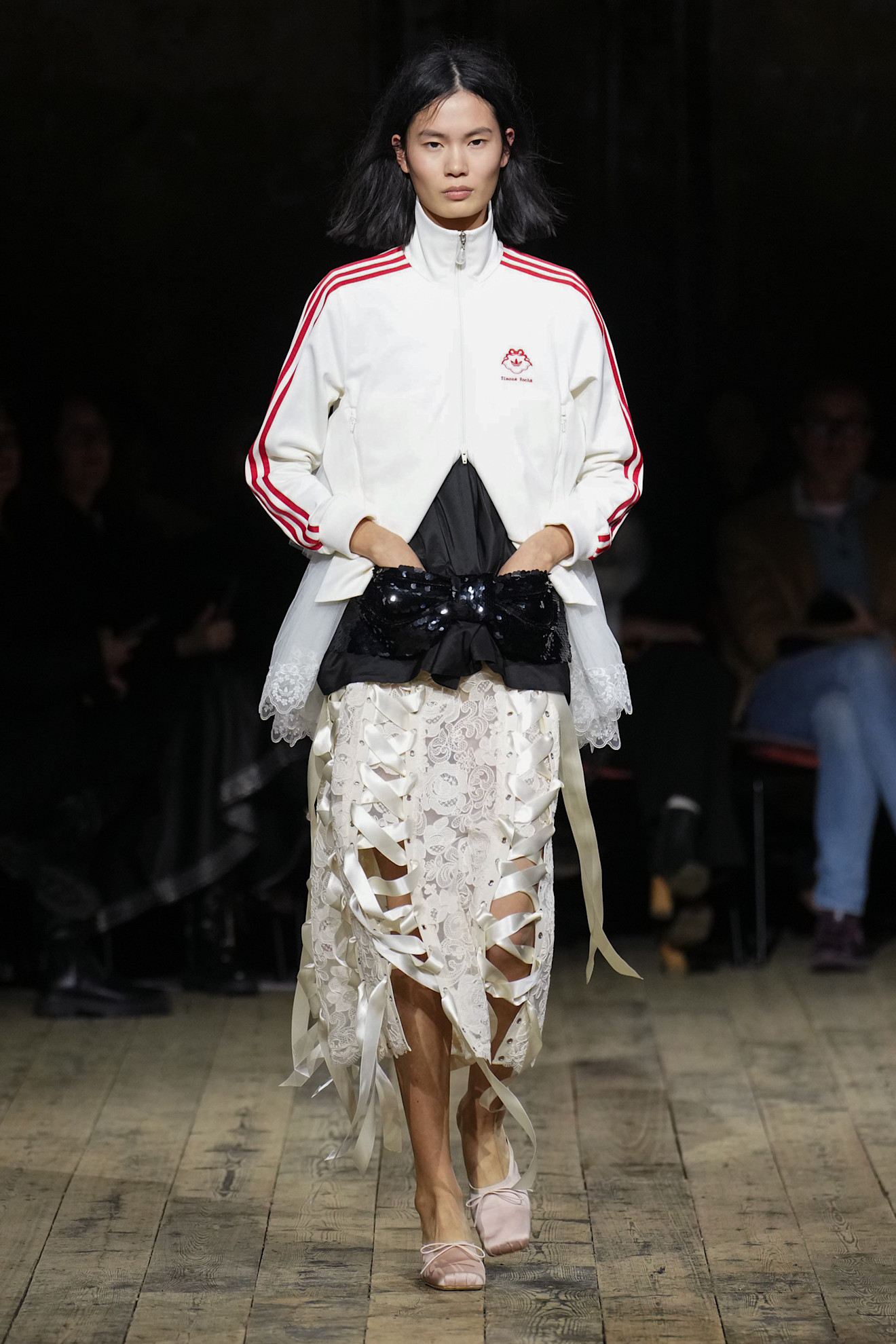 a model wearing an adidas jacket over a simone rocha skirt