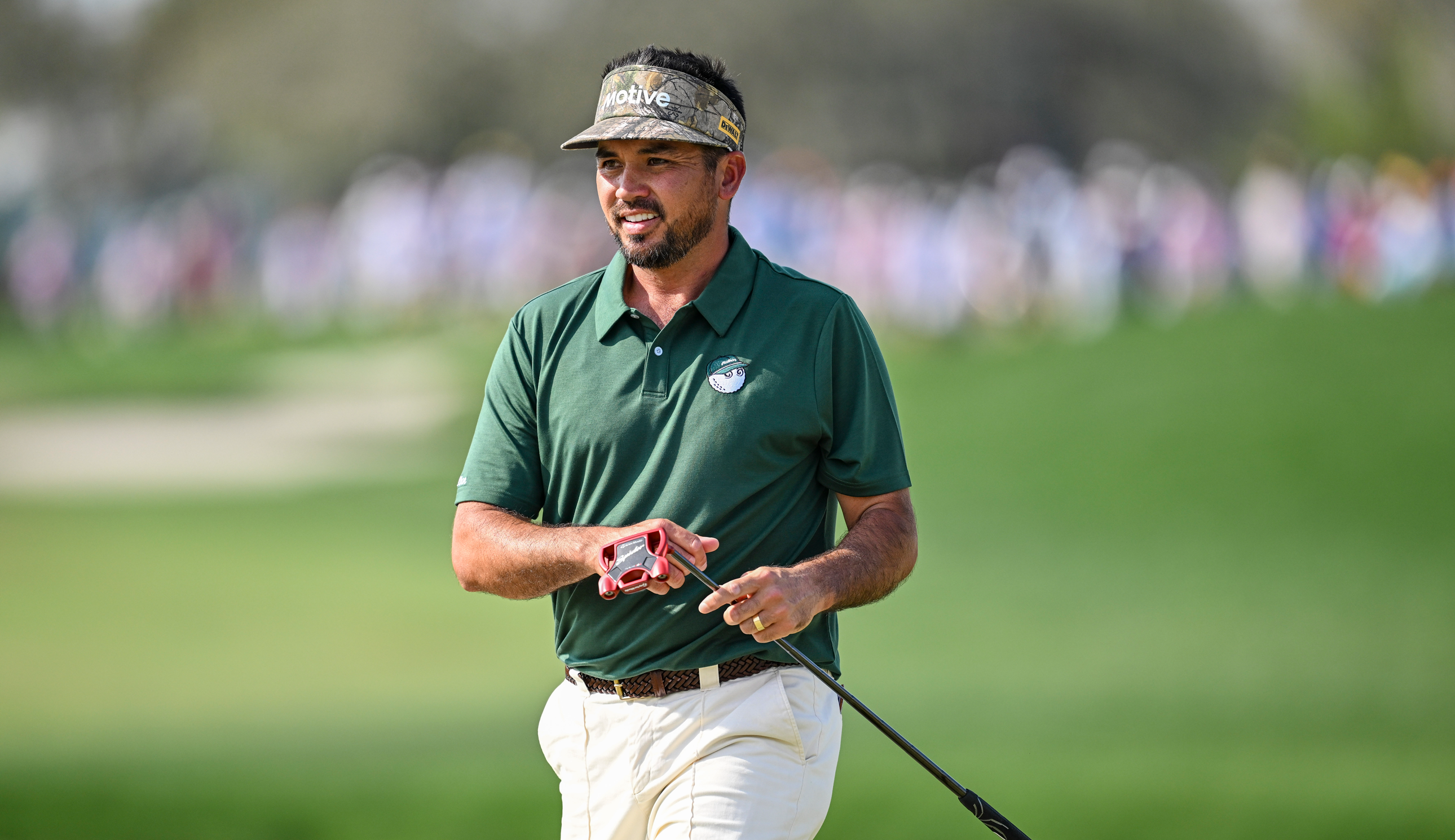 Jason Day walks off the green holding his putter