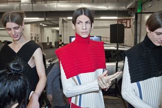 Three men in a line, who all look like they are getting ready for a show.