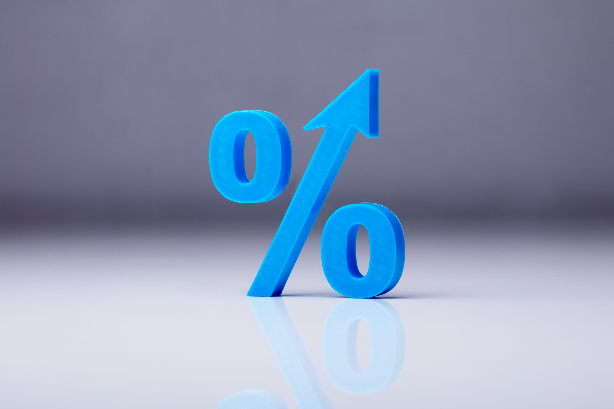 Close-up of A blue percentage symbol on a reflective gray background