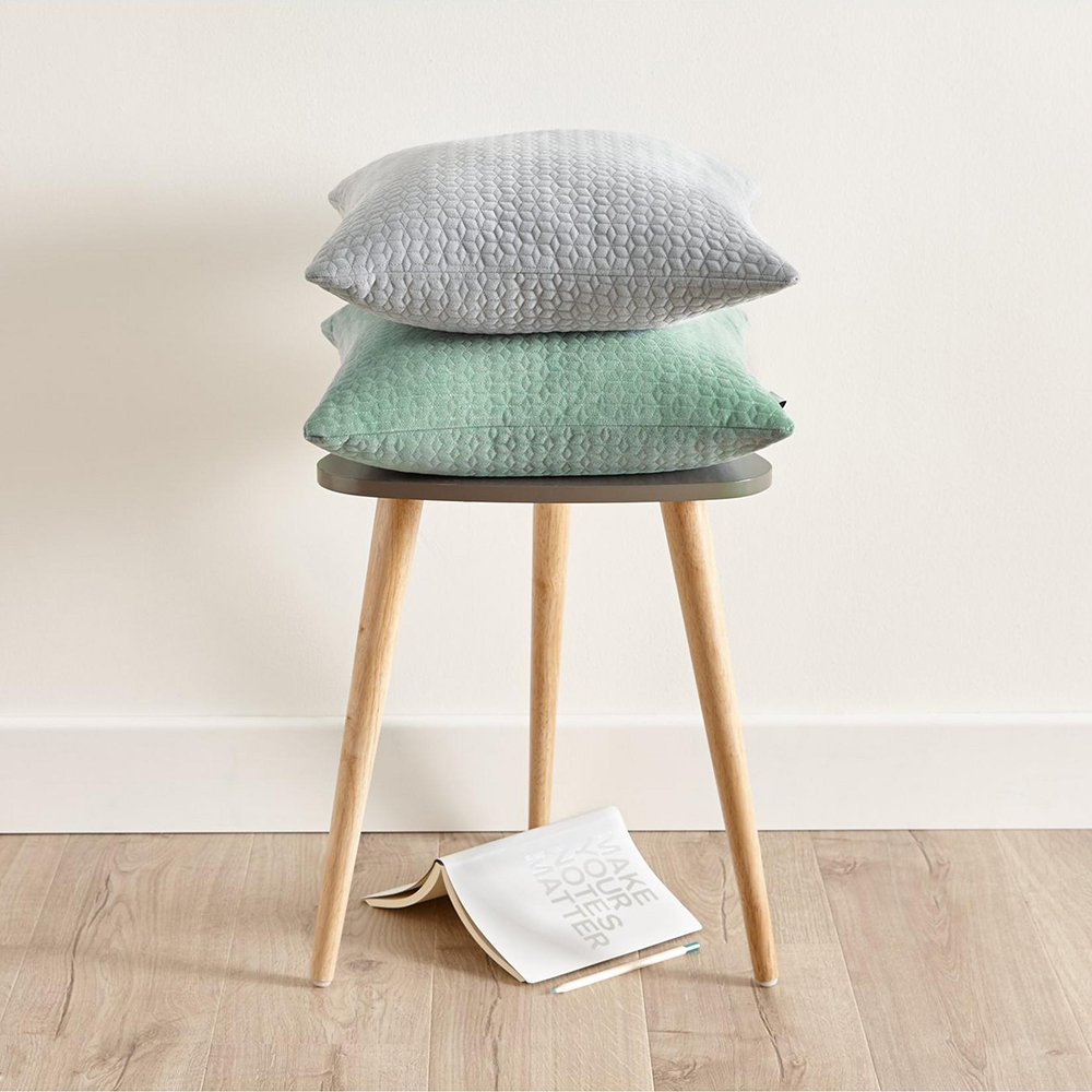 room with white wall and wooden floor and three leg table with teal colour cushions