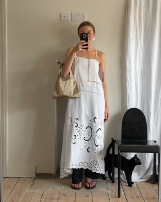 Brittany Bathgate wearing a white crochet maxi dress with pants and flip flops.