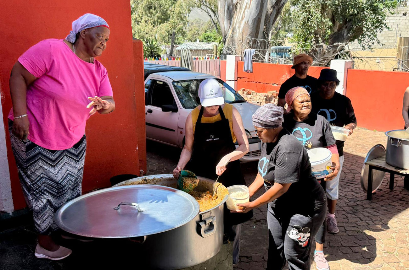 Julie serving up meals under the watchful eye of Joyce at her soup kitchen in Sir Lowry's Pass Village, funded by JEF