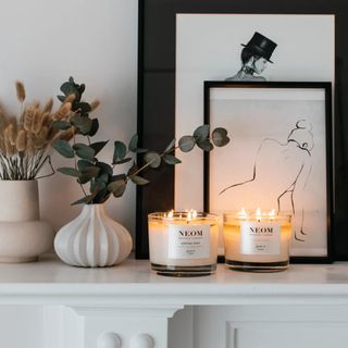 Two NEOM candles on a mantelpiece