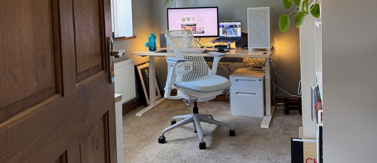 A white Sayl chair next to a standing desk.