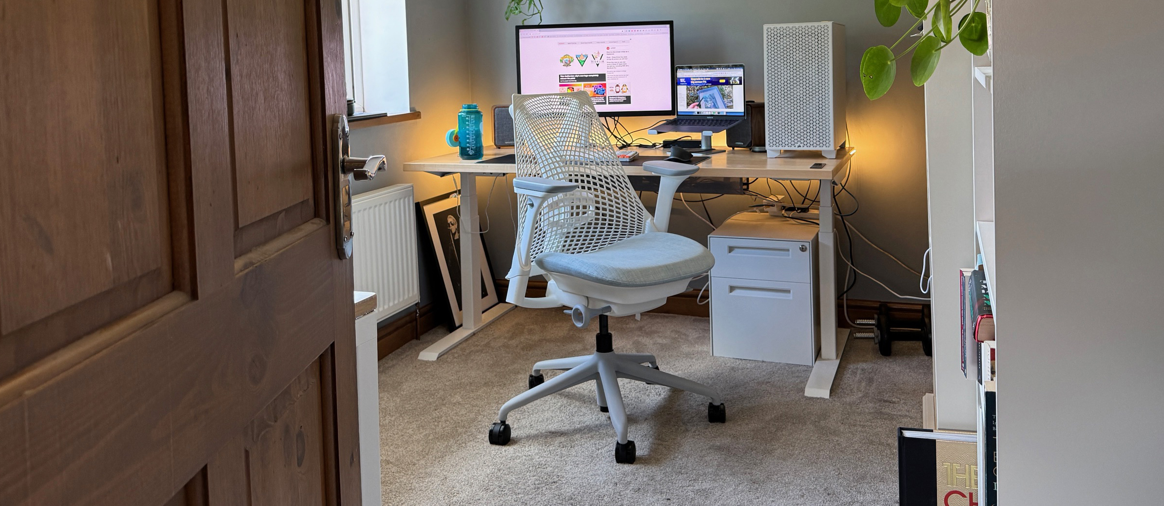A white Sayl chair next to a standing desk. 
