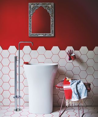 Painted red bathroom with white tiles and red grouting, tall sink with floor-standing tap