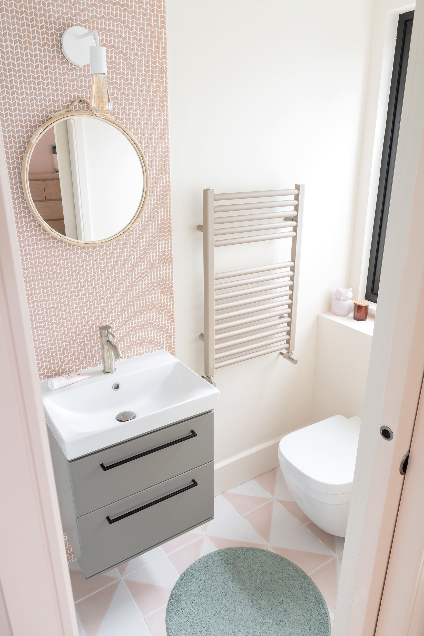 Pink tiled splash board behind sink with pink and white geometric floor