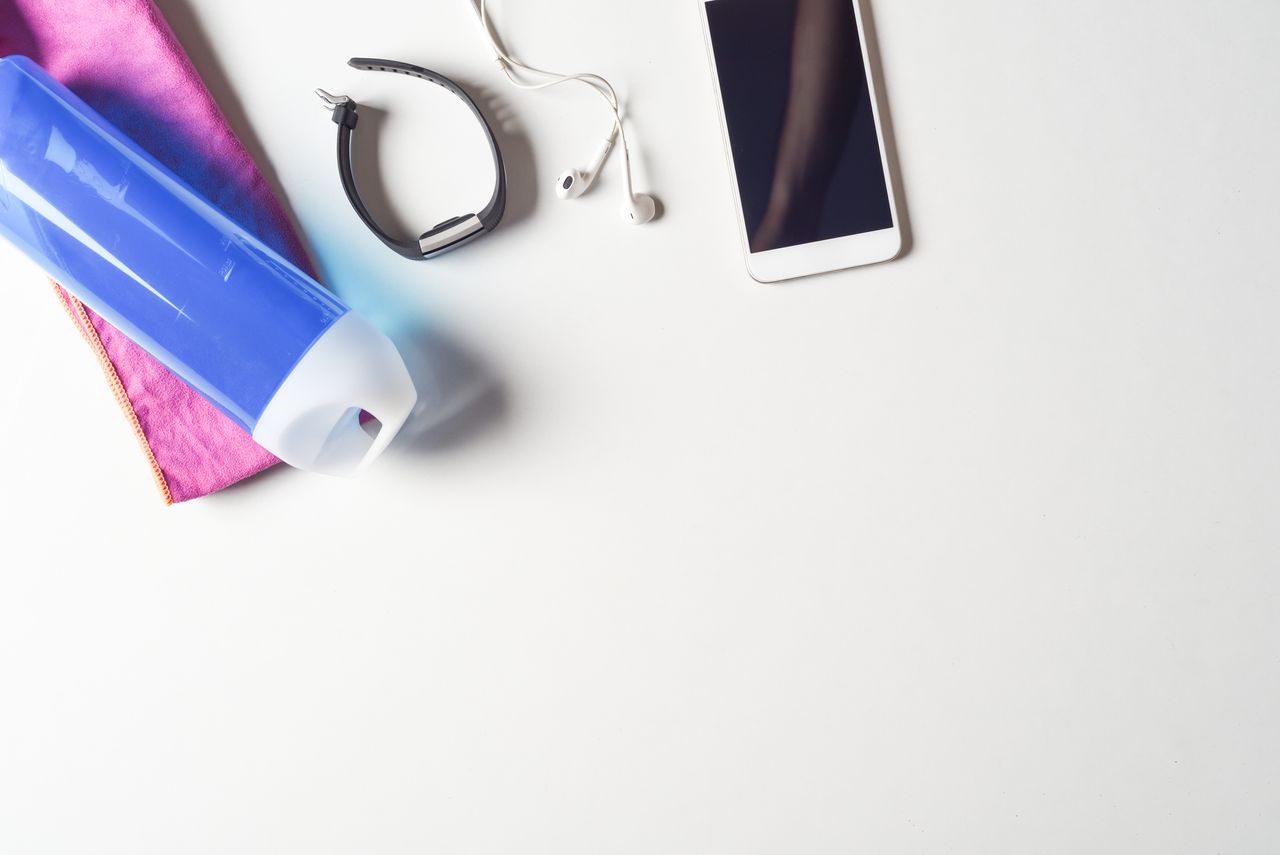 phone, headphones, fitness tracker and water bottle on a white background