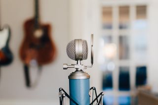 Close up of old fashioned microphone with guitar in background