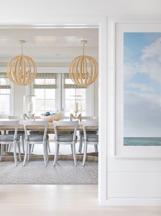 Modern country dining room with wooden, sphere cage lightshades, wooden dining table with candles in jars