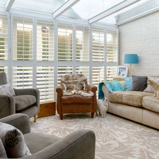 A conservatory with shutters and a brown leather armchair