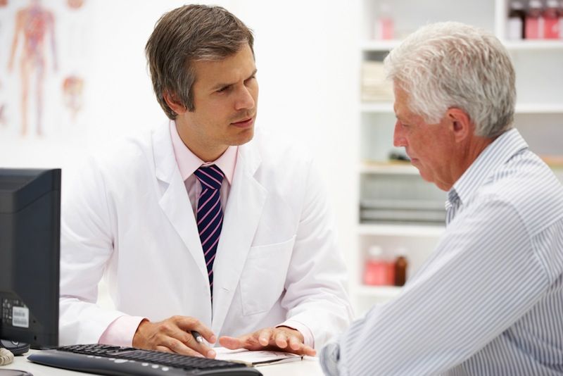 An older man talks with a doctor.