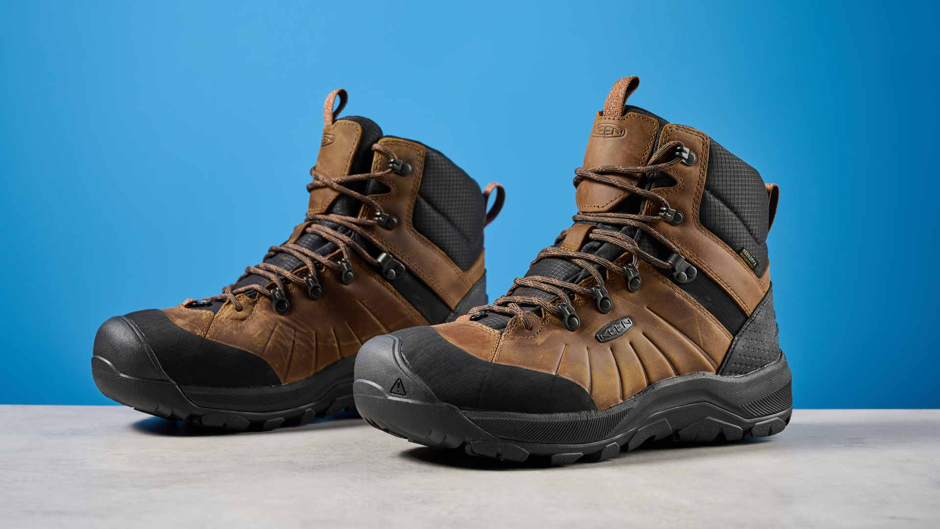 The Keen Revel IV in brown on a stone surface with a blue background