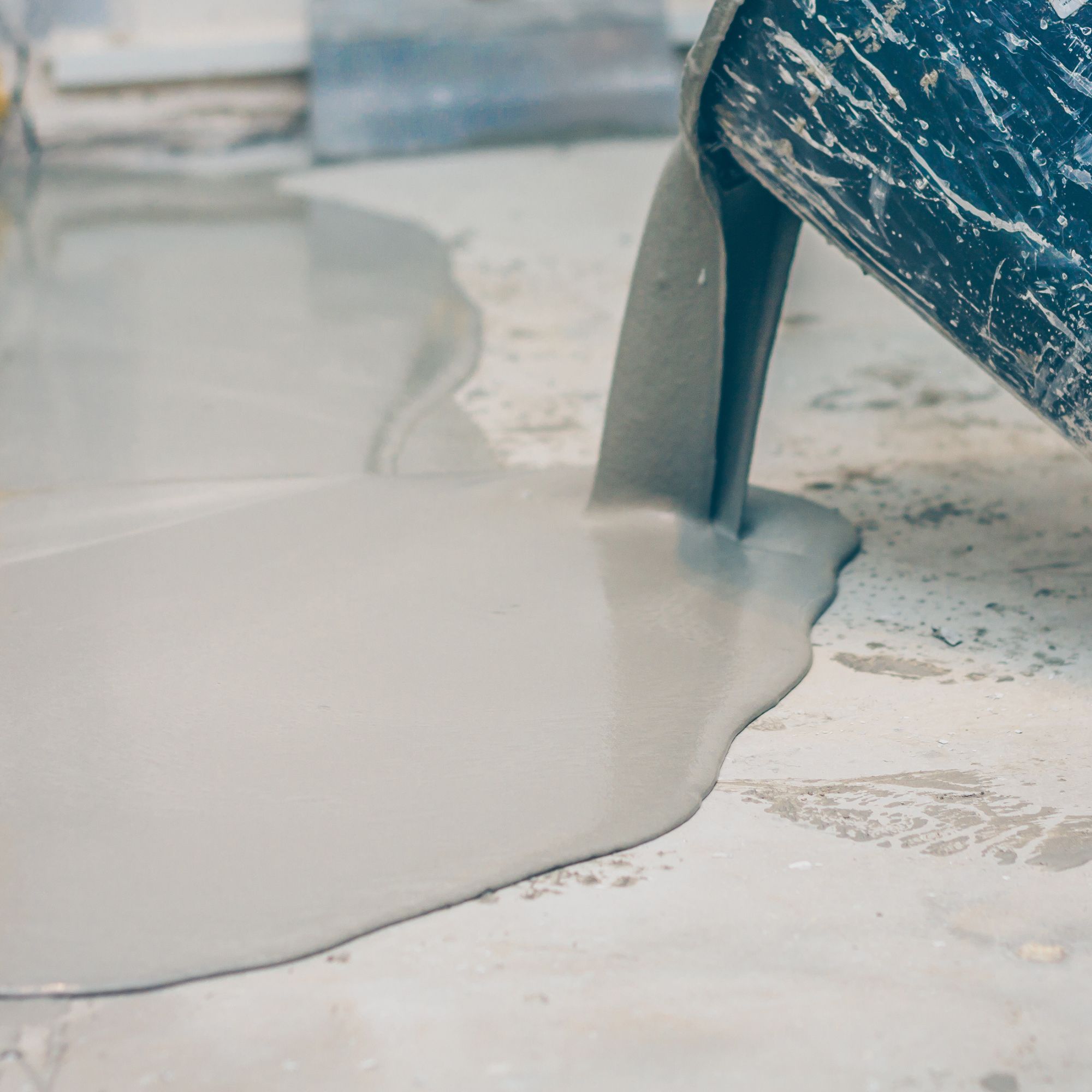 Pouring screed out of a bucket on to a floor to level it out