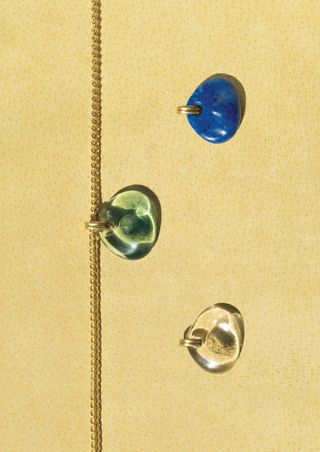 a prounis necklace on a yellow backdrop with gems floating around it