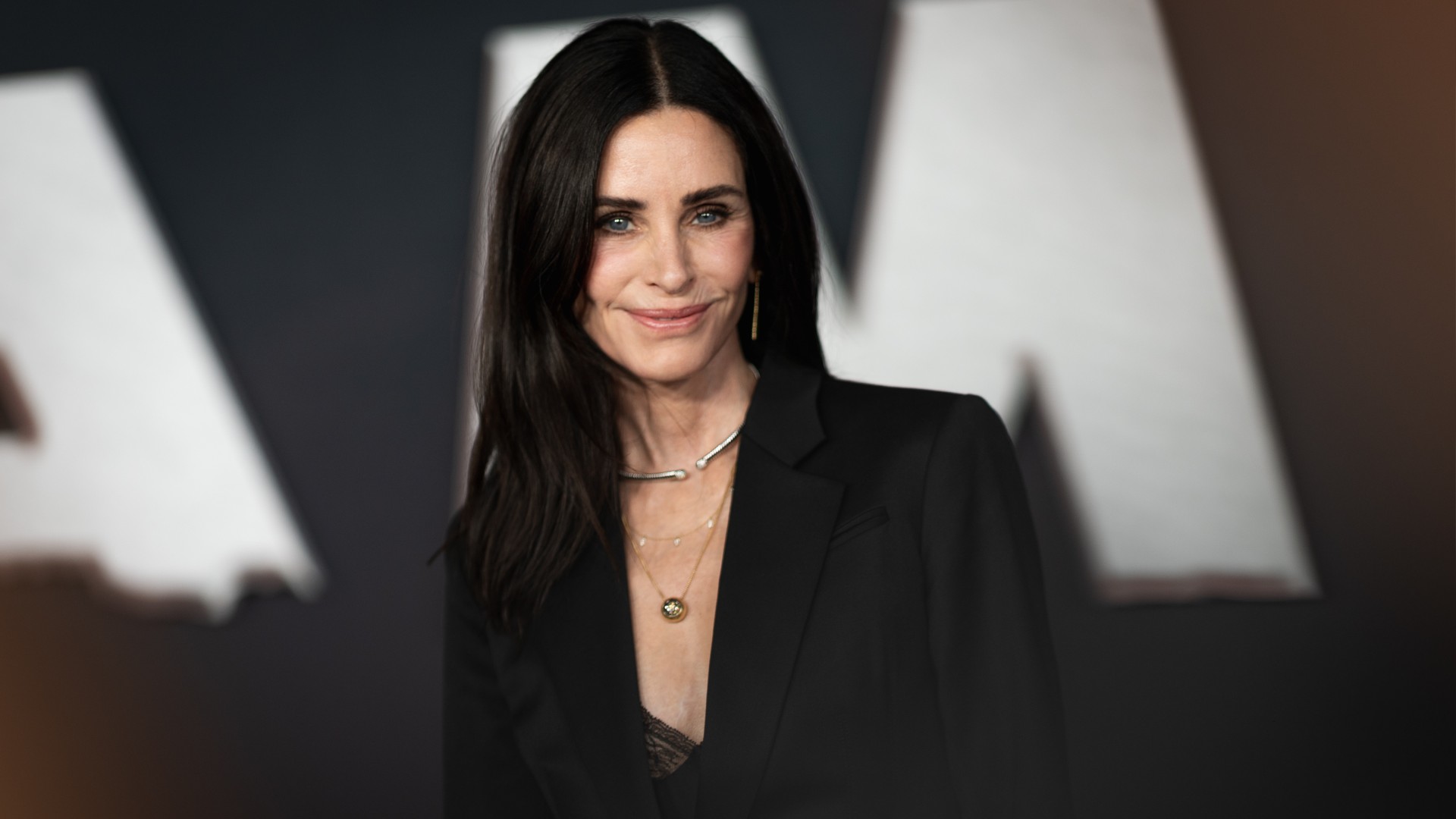 a white woman with dark hair posing for paparazzi in front of a black and white background