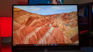 A Lenovo Legion 5i (Gen 9) gaming laptop on a desk with a red backlight, zoomed in on its open display.