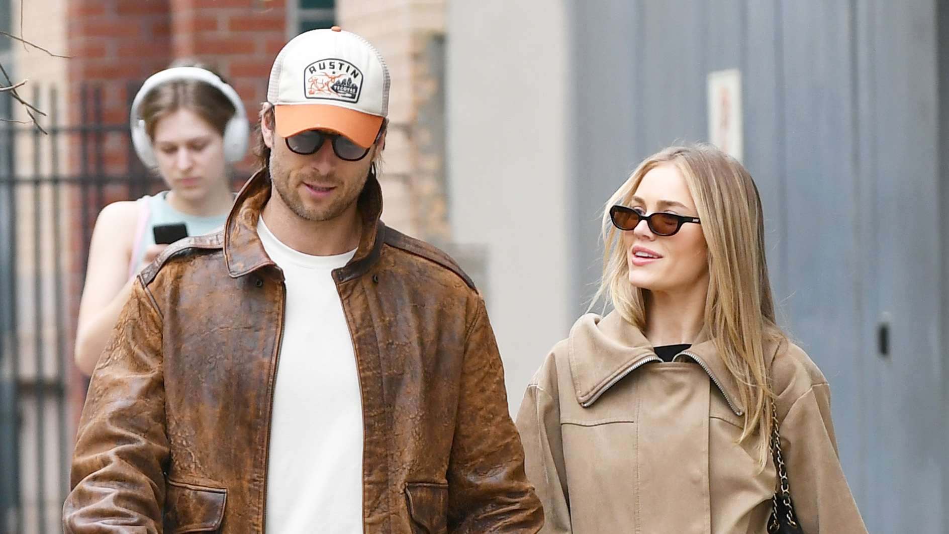Glen Powell and Michelle Randolph walking in NYC wearing tan jackets and jeans