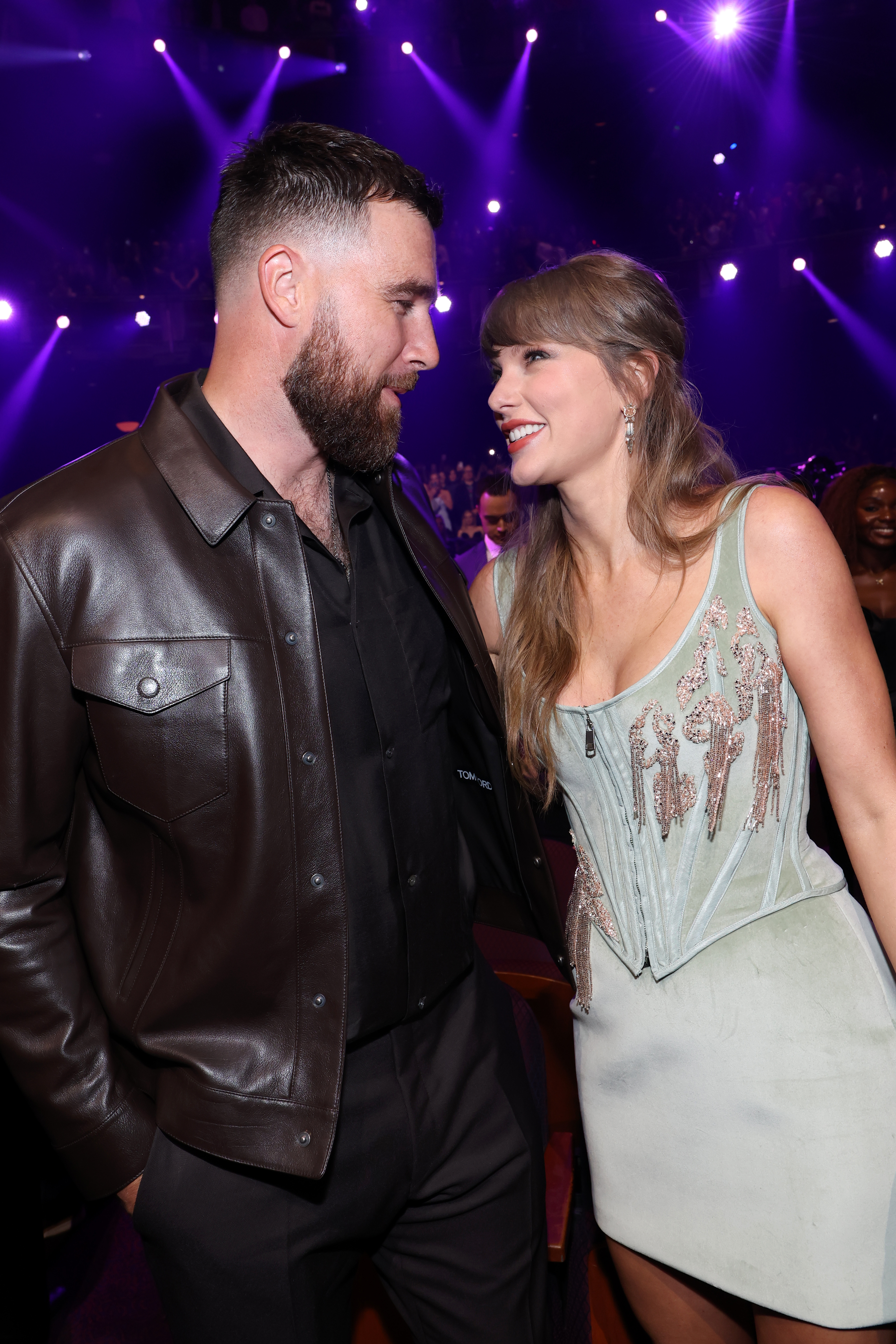 Taylor Swift and Travis Kelce smiling at each other at the Grammys