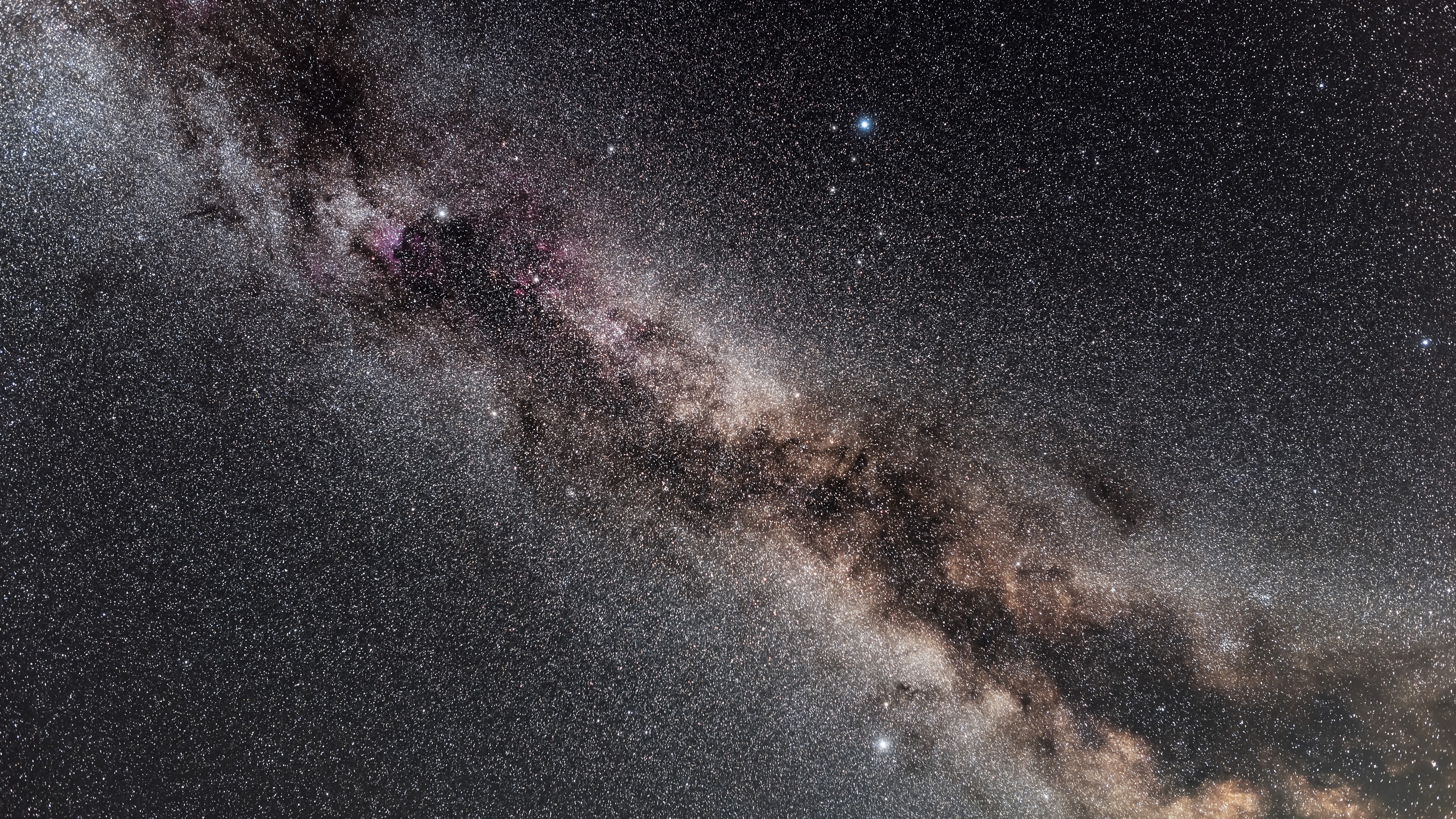 The northern summer Milky Way through the area of the Summer Triangle, showing the change in colour as the Milky Way heads south toward the dustier regions around the galactic core Deneb in Cygnus is at top, Vega in Lyra is to the upper right, and Altair in Aquila is at bottom The dark lanes of the Cygnus Rift show up well, beginning in Cygnus and splitting the Milky Way in two on south 