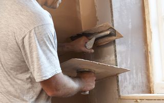 a tradeperson plastering a room