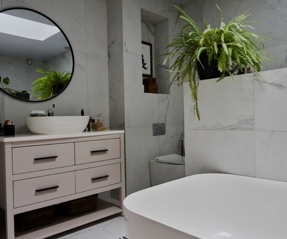 A white bathroom with porcelain tiles and a white bath and sink with a wall mirror