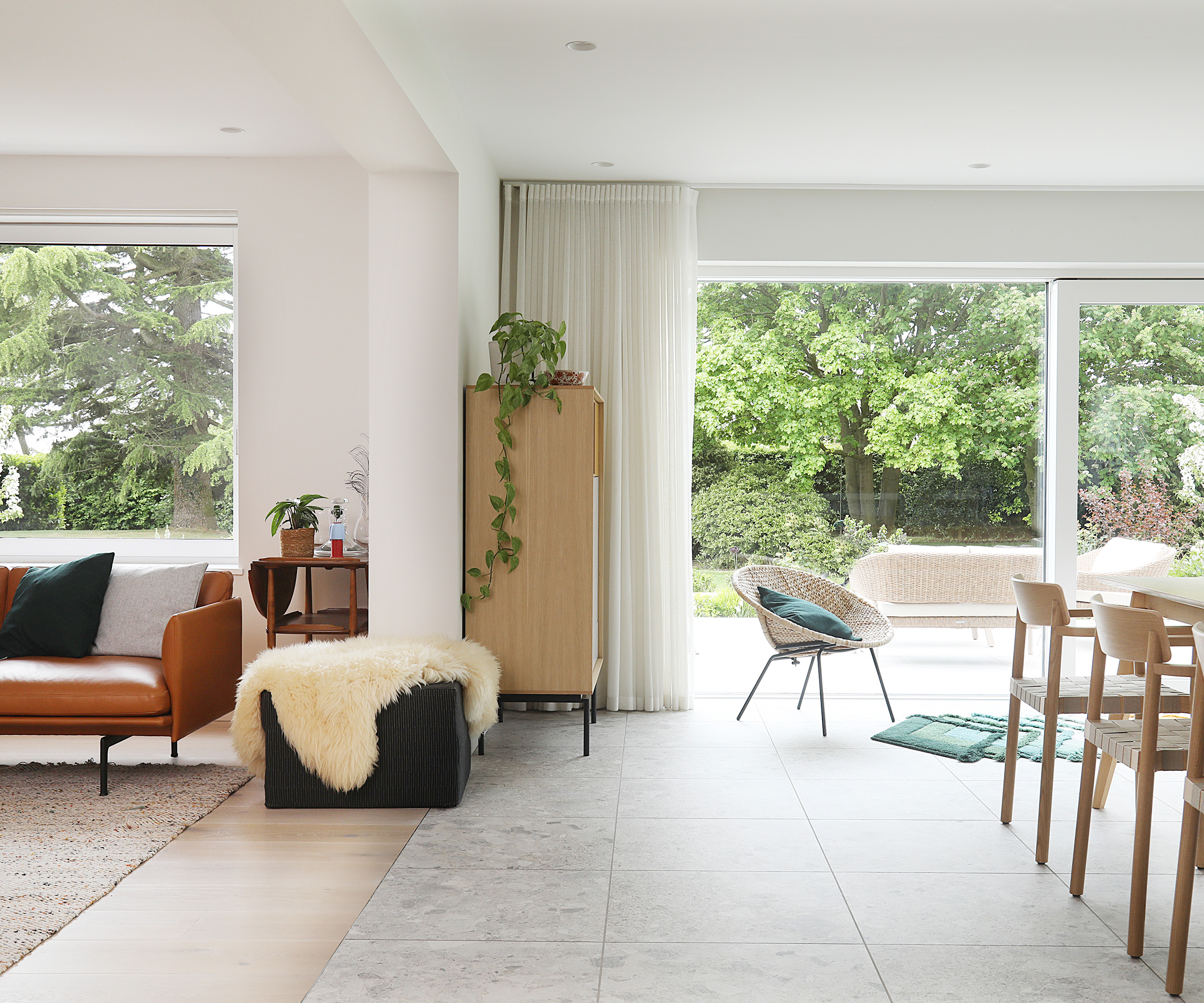 A white living room and open plan dining room space with sliding doors opening into the back garden