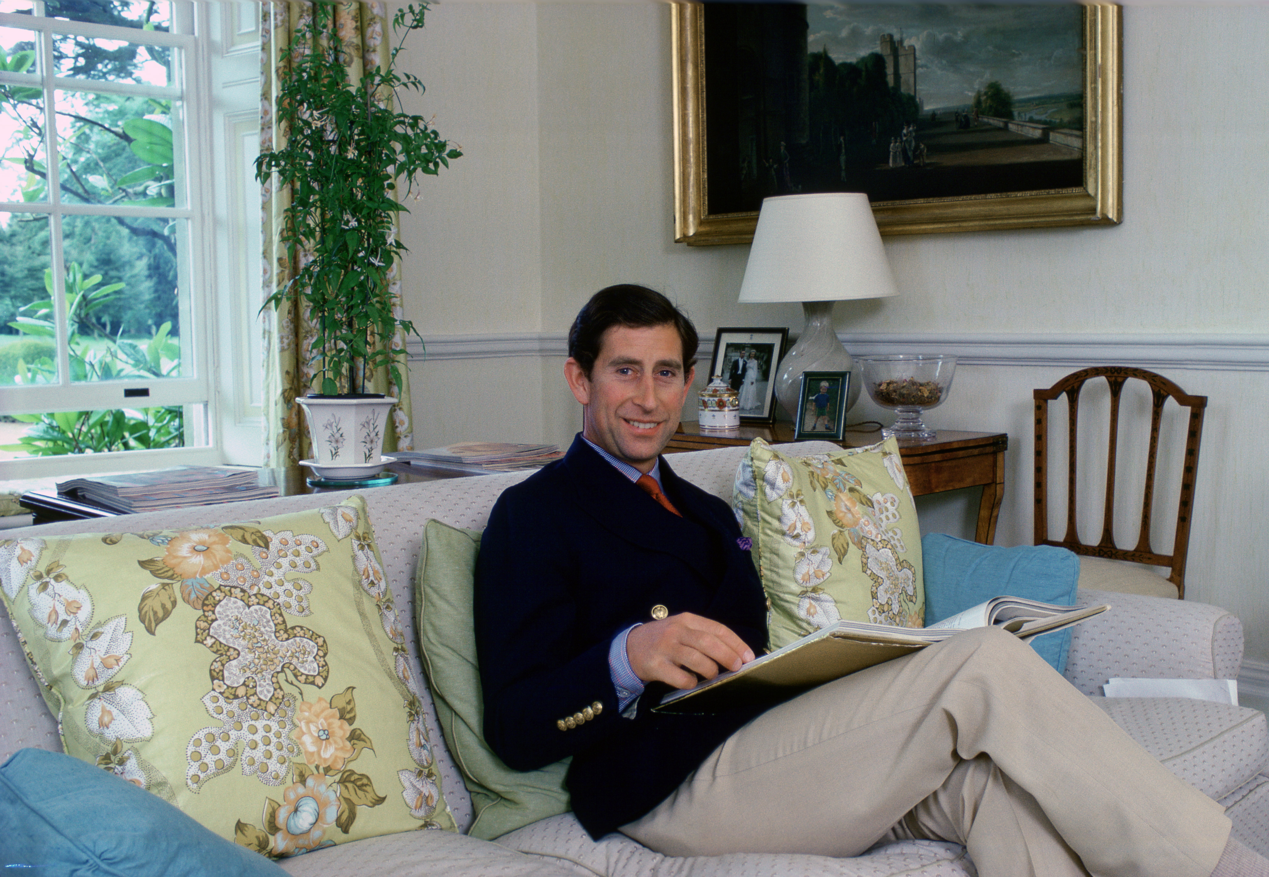 Prince Charles reading a book on a sofa at Highgrove House in 1982