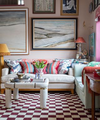 Cozy living room with off-white sofa, colorful cushions and artwork, red and white checkered carpet