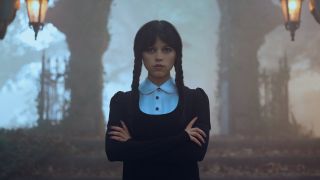 Wednesday with arms crossed outside in cemetery in Wednesday Season 2