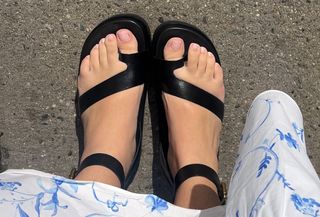 Woman wears black Frankie4 sandals on street with white-and-blue floral-printed maxi dress