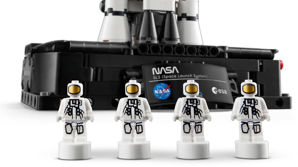 Four miniature Astronauts are placed in front of a black platform displaying a plaque showing the NASA and ESA logos.