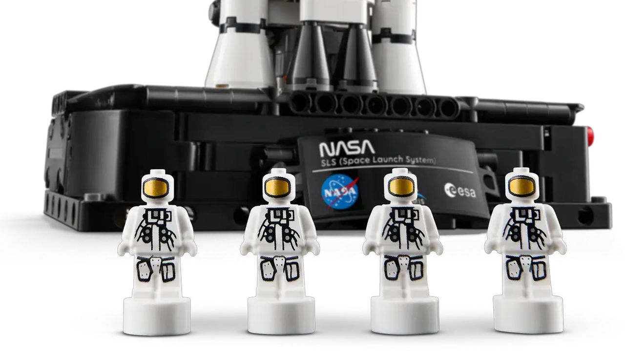 Four miniature Astronauts are placed in front of a black platform displaying a plaque showing the NASA and ESA logos.