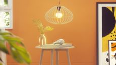 Yellow wall with a smart light bulb pendant shown