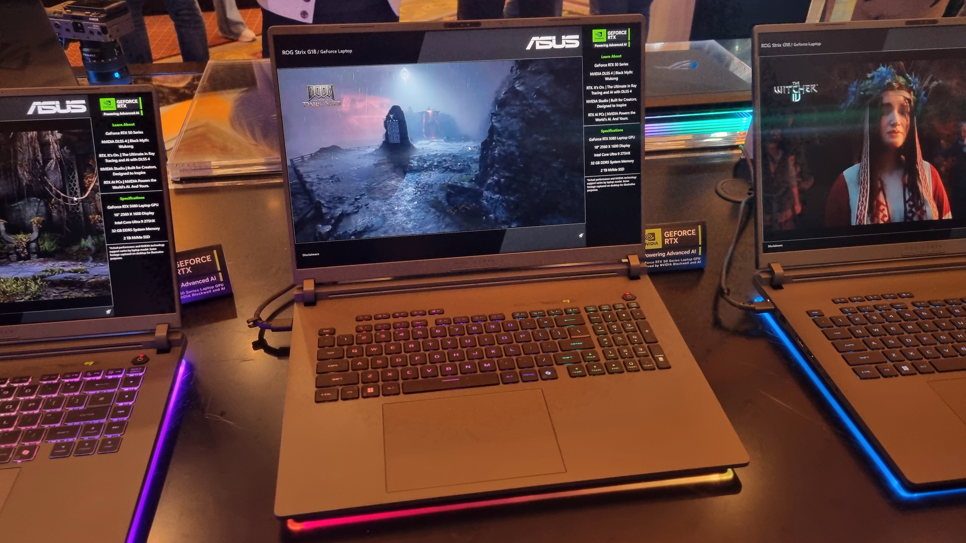 The Asus ROG Strix Scar 18 sitting on a table with two other laptops at CES 2025.