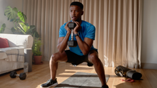 A man performing a dumbbell goblet squat in his living room